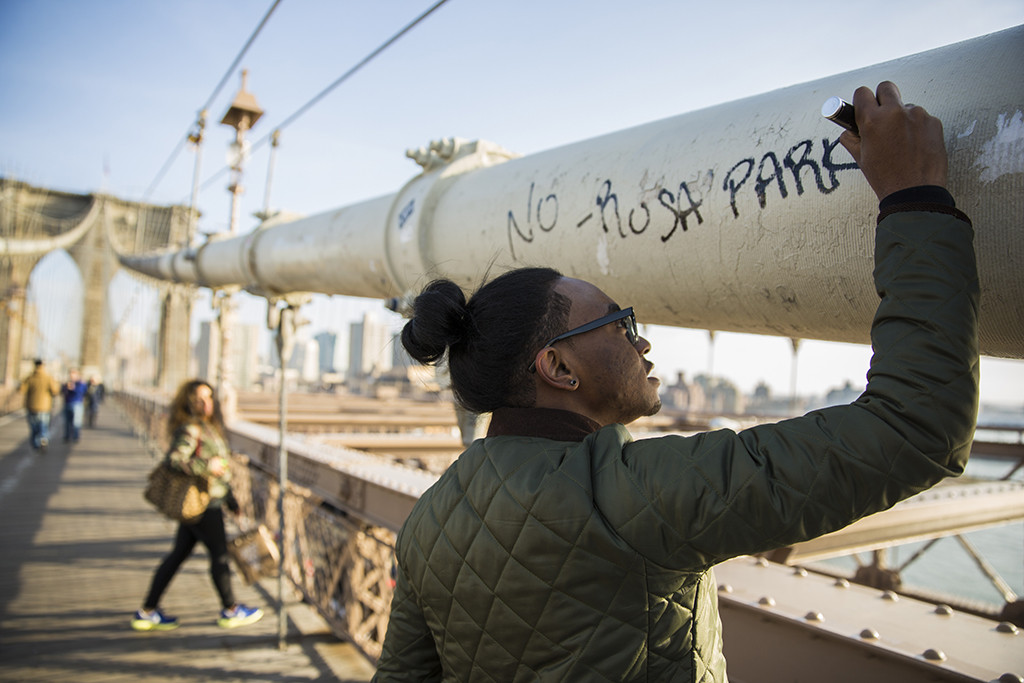 SECOND PLACE: Mark Watkins, Georgia College and State University (Macon McGinley, adviser) — New York native Tajjy Melendez, 21, signs his tagline to the Brooklyn Bridge while his girlfriend Yessinia Paidilla, 19, watches.