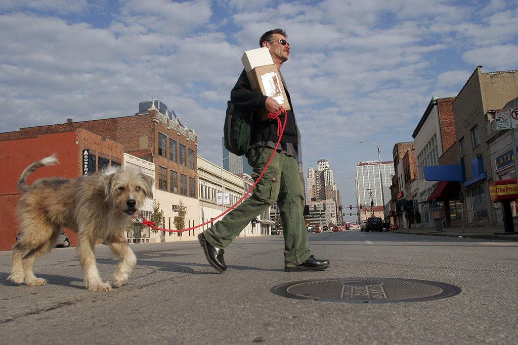 SECOND PLACE: Nick Loomis, University of Iowa — Kansas City resident Tom Deatherage walks his dog, Max, across Grand Blvd. on the way back to his art gallery after gathering salvaged materials for his artwork on Saturday morning.