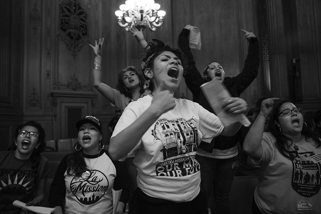 At nearly midnight on June 2, 2015, Alondra Aragon, center, led a chant in City Hall in San Franciso, Calif. immediately after the Mission Moratorium was voted on. The final vote was 7-4 in favor of the moratorium, but the measure needed nine votes to be passed as an "interim emergency ordinance." Aragon and dozens of other Mission Moratorium supporters had filled the room for over eight hours that day. Of the supporters, San Francisco Board of Supervisors Member John Avalos said, "The rich fabric of the Mission is what is here today." Katy Tang, the supervisor from District 4, said, "This was incredibly moving for me, although at times emotional, very inspirational."